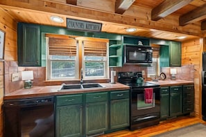 A kitchen with wooden cabinets, a microwave, a stove, and a sink. - The Equestrian Hideaway (8-minutes from TIEC)! (Rutherfordton)