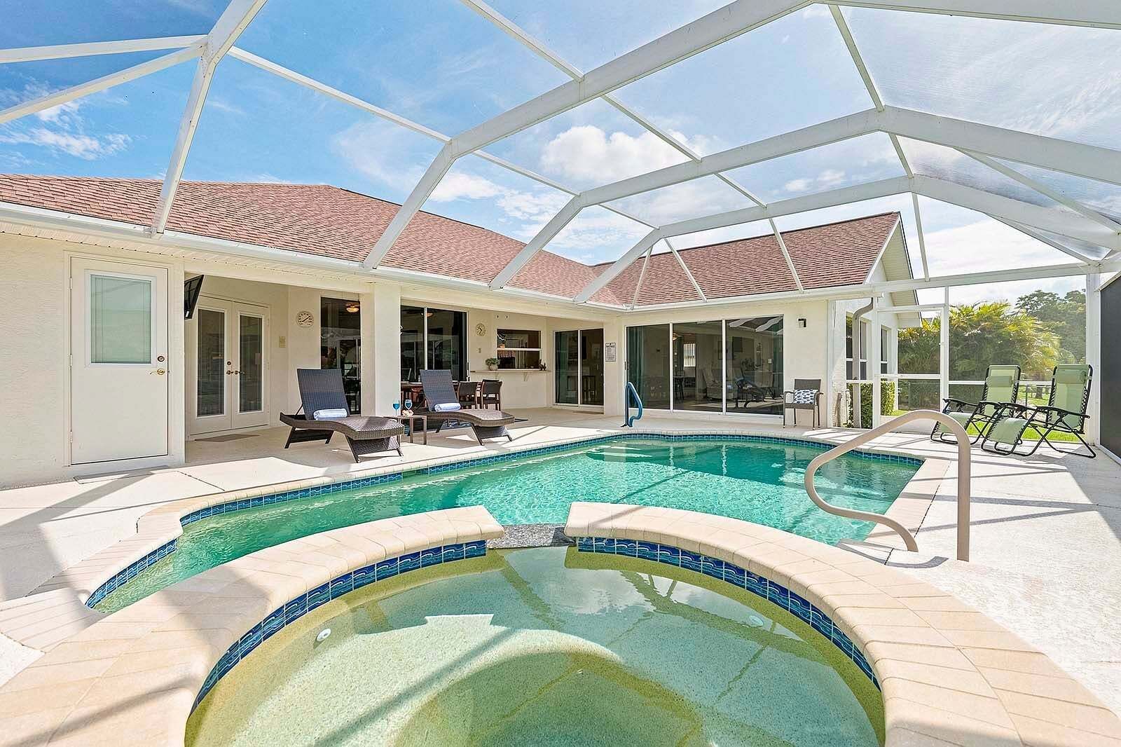 Una piscina interna con soffitto in vetro, poltrone relax e solarium piastrellato.