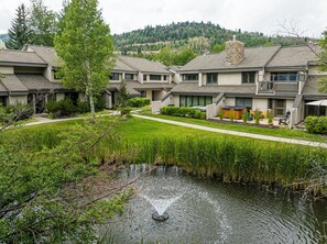 A residential complex with multiple houses, a well-maintained lawn, and a small pond with a fountain. - Spacious 4BR Deer Valley condo with 3.5 baths, ideal for 12 guests. (Park City)