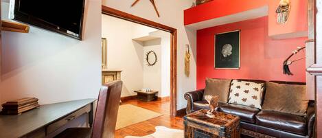 A living room with a leather sofa, a coffee table, a flat-screen TV, and various decorative items on the walls.