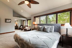 A bedroom with a large bed, a ceiling fan, a window with a view of trees, and a mirror. - Spacious 4BR Deer Valley condo with 3.5 baths, ideal for 12 guests. (Park City)