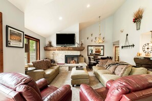 A spacious living room with a fireplace, leather sofas, a flat-screen TV, and a dining area. - Spacious 4BR Deer Valley condo with 3.5 baths, ideal for 12 guests. (Park City)