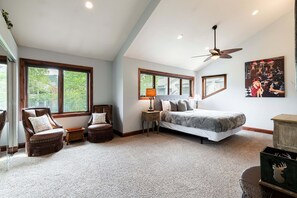 A bedroom with a bed, two chairs, a nightstand, a ceiling fan, and a painting on the wall. - Spacious 4BR Deer Valley condo with 3.5 baths, ideal for 12 guests. (Park City)