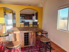 A kitchen with wooden cabinets, a central island with stools, and a patterned rug. - Mountain View Santa Fe Villa with Private Spa, Heated Pool by Joshua Tree (Desert Hot Springs)