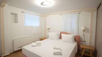 A hotel room with a bed, a bedside table, a nightstand, a window, and a wall-mounted lamp.