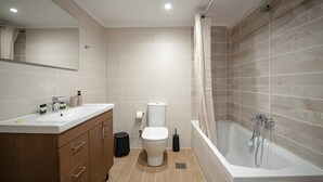Une salle de bain moderne équipée d’une baignoire, de toilettes et d’un meuble-lavabo.