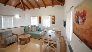 Un vaste espace de vie doté d’un haut plafond en bois, d’un ensemble de canapés, d’une table à manger et d’un grand tableau accroché au mur.