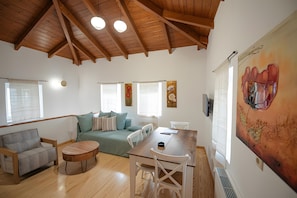 A spacious living area with a high wooden ceiling, a sofa set, a dining table, and a large painting on the wall. - Dervisia Stonehouse 4 Apartment with Lake View, Wi-Fi, and Air Conditioning (Lazarata)