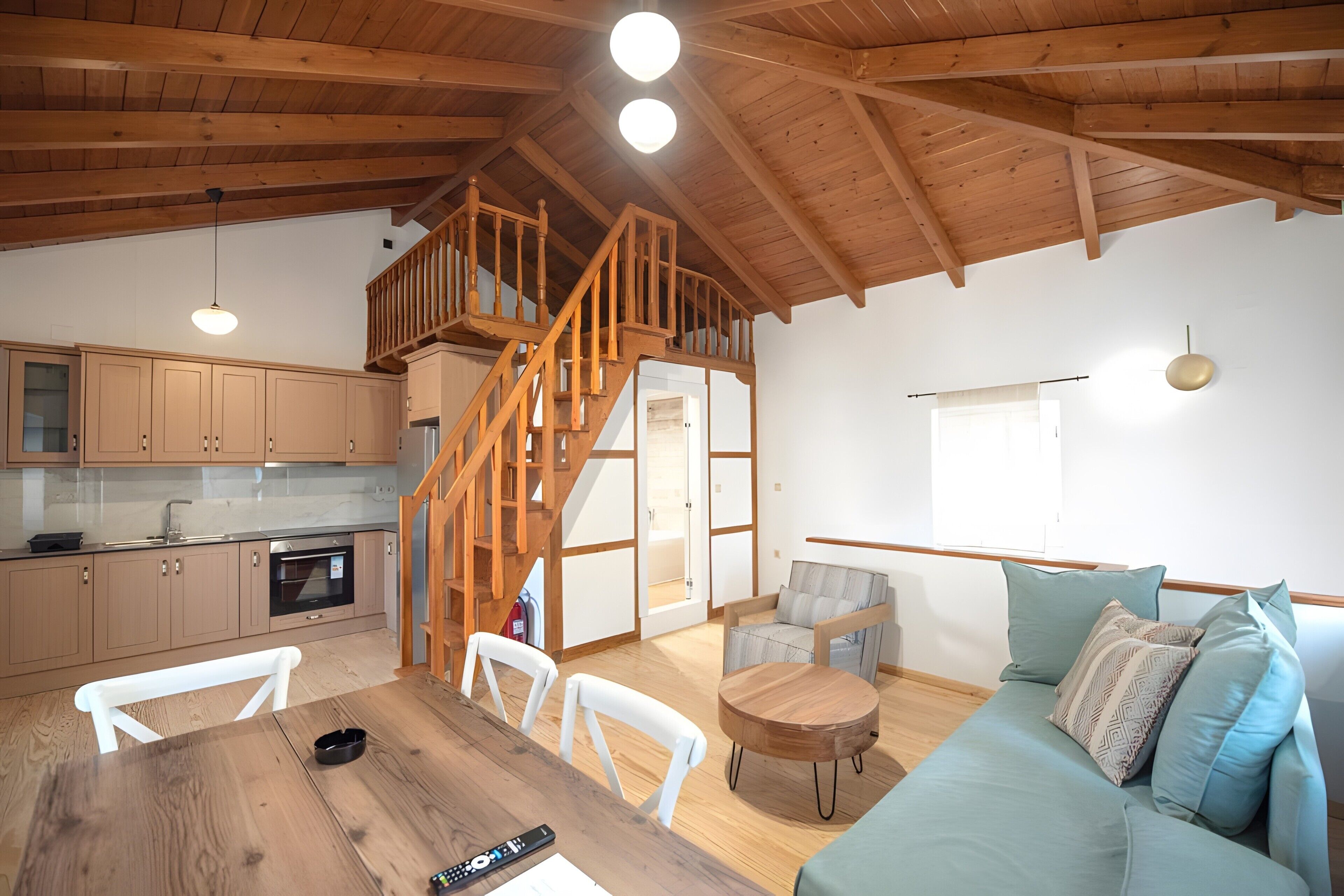 A spacious living area with a wooden staircase, a kitchen with modern appliances, and a cozy seating area.