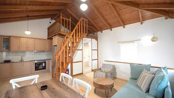 A spacious living area with a wooden staircase, a kitchen with modern appliances, and a cozy seating area.