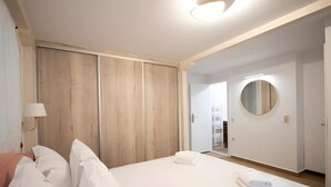 Une chambre d’hôtel comprenant un lit, une armoire, un miroir et une porte donnant sur une salle de bain.