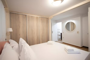 A hotel room with a bed, a wardrobe, a mirror, and a door leading to a bathroom. - Dervisia Stonehouse 4 Apartment with Lake View, Wi-Fi, and Air Conditioning (Lazarata)