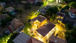 Vue aérienne d’un quartier résidentiel avec des maisons, une allée et une maison bien éclairée au centre.