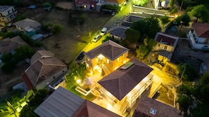 An aerial view of a residential area with houses, a driveway, and a well-lit house in the center. - Dervisia Stonehouse 4 Apartment with Lake View, Wi-Fi, and Air Conditioning (Lazarata)