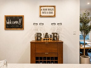 Zona de bar amb un armari de fusta, un cartell de benvinguda i un rètol que diu: 'Un home entra a un bar'.