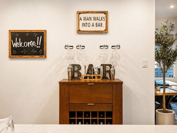 A bar area with a wooden cabinet, a welcome sign, and a sign above stating 'A man walks into a bar.' - Old Town 5 Min, Heated Pool & Spa & Putting Green (Scottsdale)