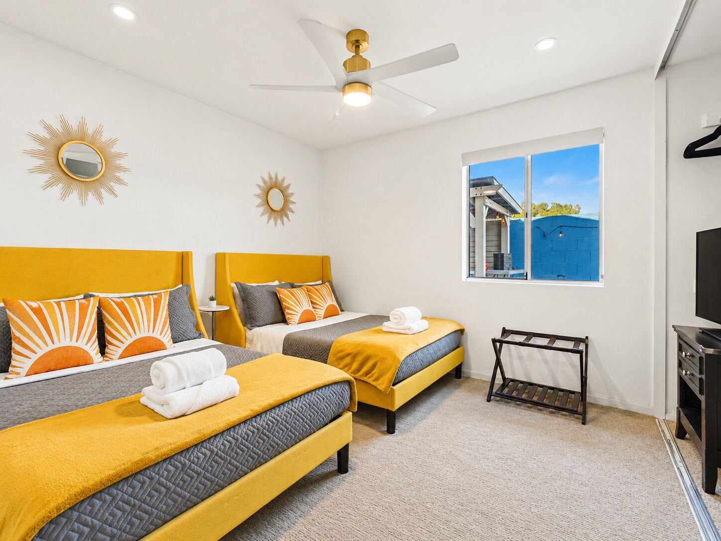 A hotel room with two beds, a ceiling fan, a window with a view, and a TV.
