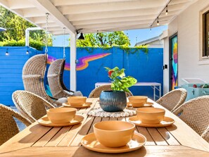 An outdoor dining area with wicker chairs, a table set with bowls and plates, and a potted plant. - Old Town 5 Min, Heated Pool & Spa & Putting Green (Scottsdale)