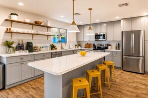 A modern kitchen with a central island, bar stools, stainless steel appliances, and wooden flooring. - Old Town 5 Min, Heated Pool & Spa & Putting Green (Scottsdale)