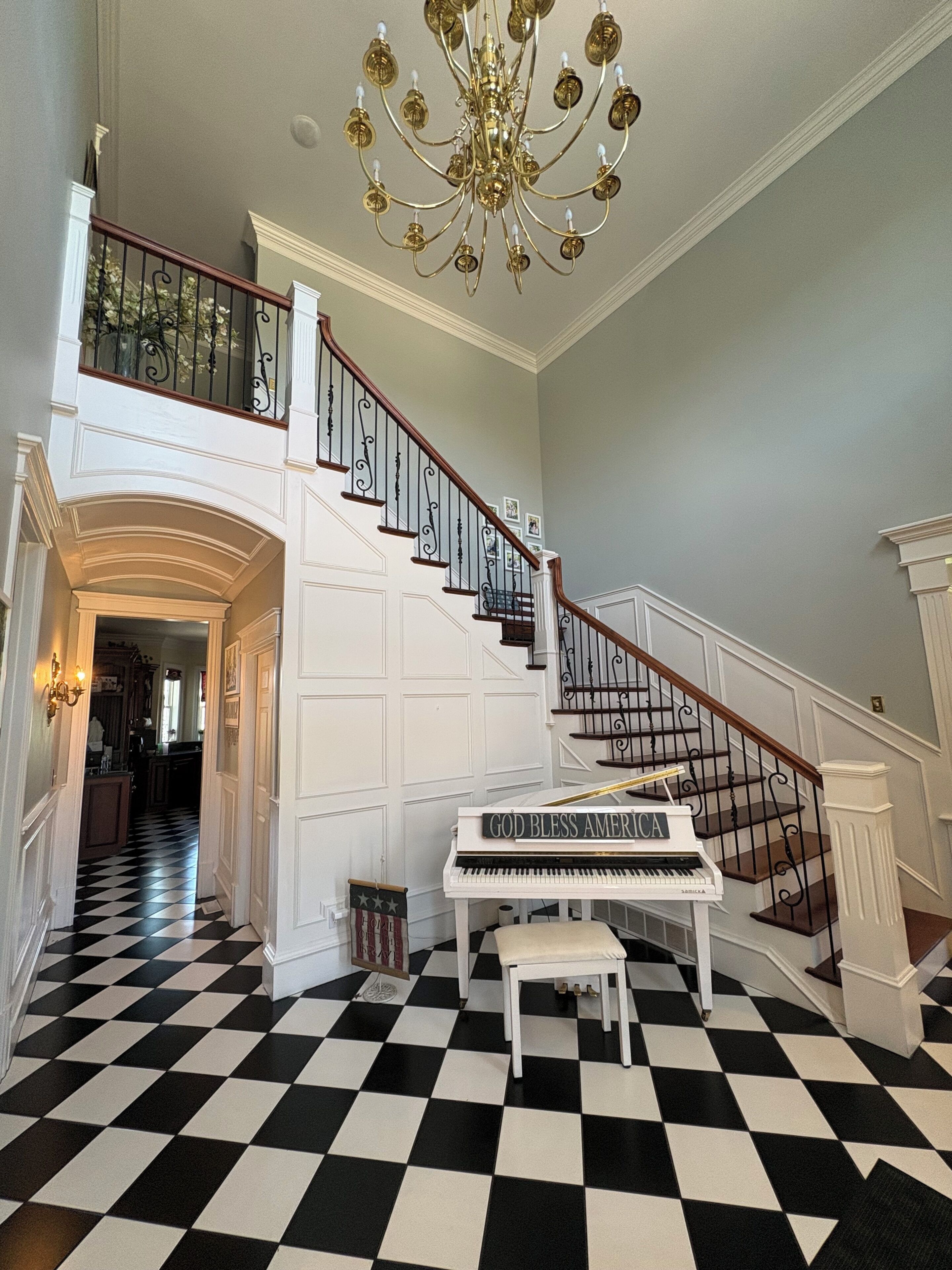 A grand staircase with a piano and a chandelier.