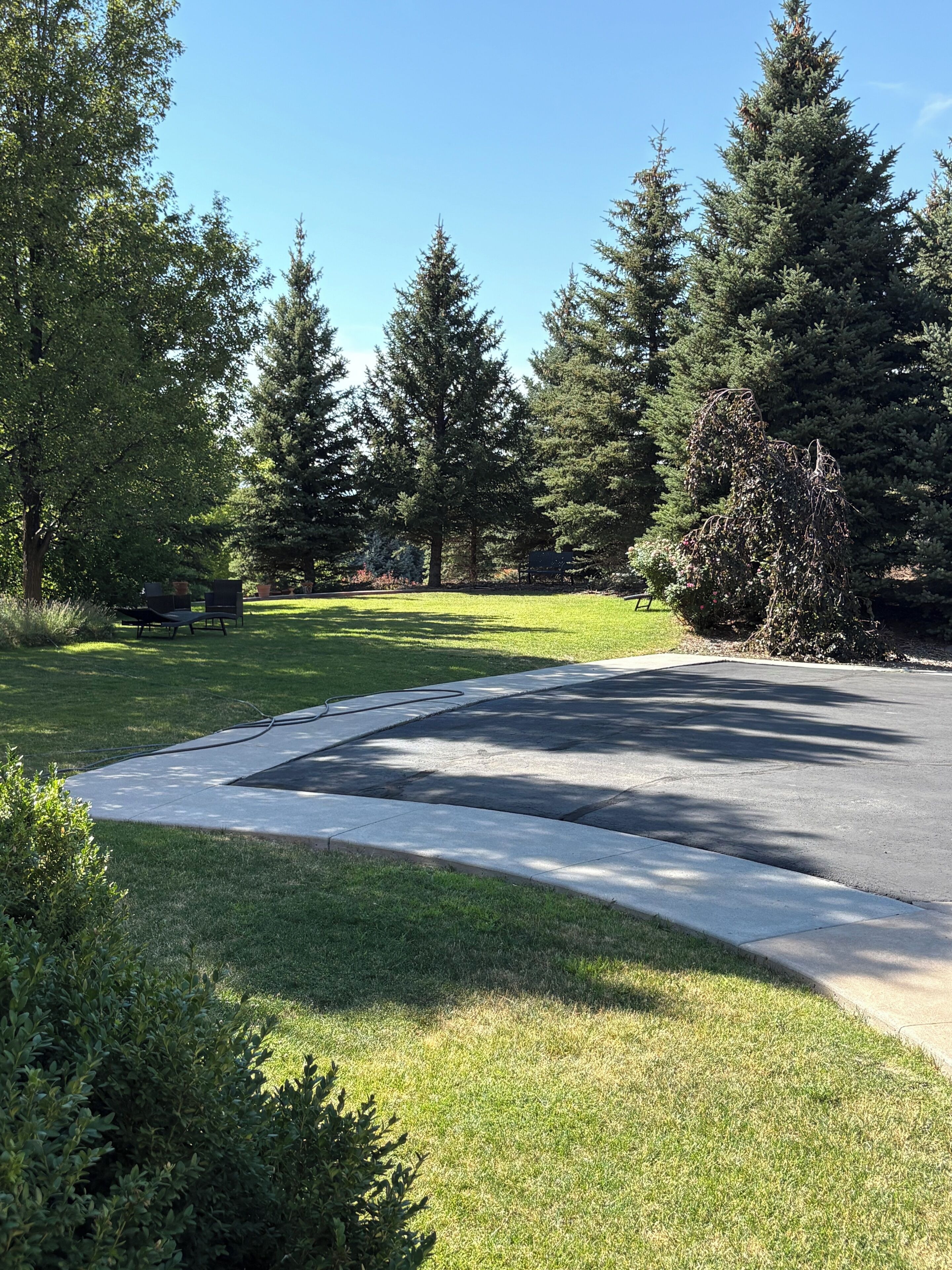 Uma entrada residencial com acesso circular, cercada por gramado bem cuidado e árvores.