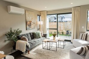A living room with a sofa, a coffee table, and a potted plant. - Prime Location | Modern Comfort | Pools Close - HS6926 (Hanmer Springs)
