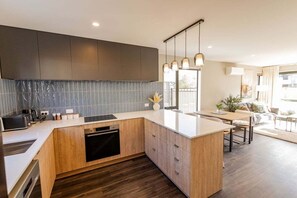A modern kitchen with a central island, wooden cabinets, and a backsplash. - Prime Location | Modern Comfort | Pools Close - HS6926 (Hanmer Springs)