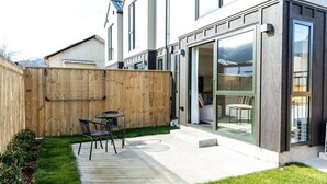 Ein modernes Haus mit einer Terrasse, einem Holzzaun und einer Glastür, die zu einem Raum führt.