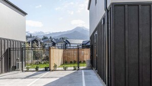 Un pati tancat amb una vista de muntanyes, un camí pavimentat i un edifici de façana fosca.