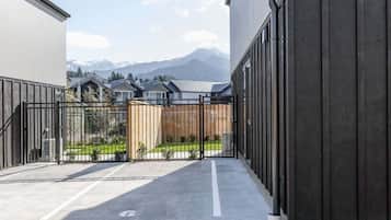 A gated courtyard with a view of mountains, a paved walkway, and a building with a dark facade.