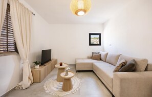 A modern living room with a sofa, a television, a round coffee table, and a hanging light fixture. - Gorgeous home in Kornati with WiFi (Kornati)