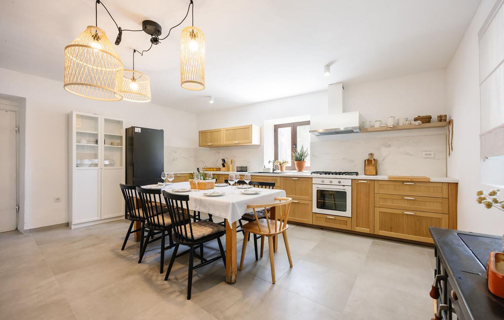 Een moderne keuken met een eethoek, met een centraal eiland, houten kastjes en hanglampen.