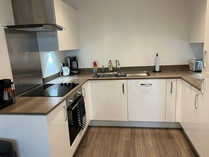 Eine moderne Küche mit weißen Schränken, einer Edelstahl-Dunstabzugshaube, einer Kaffeemaschine und einem Toaster.