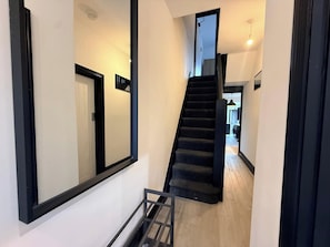 A modern interior with a staircase leading to a second floor, a door, and a hallway. - House Sleeps 6 with Patio (Cardiff)