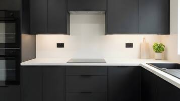 A modern kitchen with black cabinets, a white countertop, and a built-in oven.