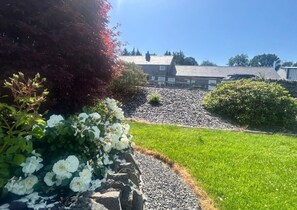 A garden with white flowers and a stone wall. - Luxury Holiday cottages Sleeps 10 (Ystrad Meurig)