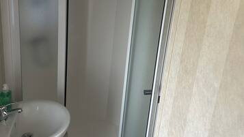 A bathroom with a white sink, a glass shower enclosure, and a towel rack.