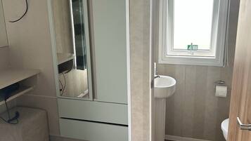 A bathroom with a toilet, sink, and mirror.
