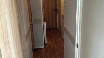 A hallway with wooden flooring, white walls, and a door at the end.