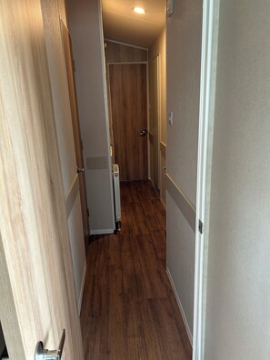 A hallway with wooden flooring, white walls, and a door at the end.