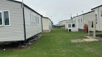 A row of mobile homes with a grassy lawn in between.