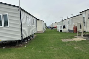 A row of mobile homes with a grassy lawn in between.