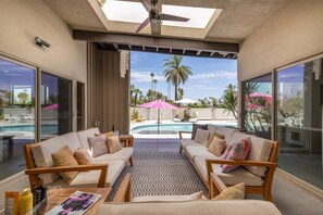 Eine sonnige Terrasse mit Pool, zwei Sofas und einem Deckenventilator.