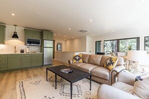 A modern kitchen with green cabinets, a black pendant light, and a built-in microwave. - Pond-View Guest House | River Access, 2 Kings (Durango)