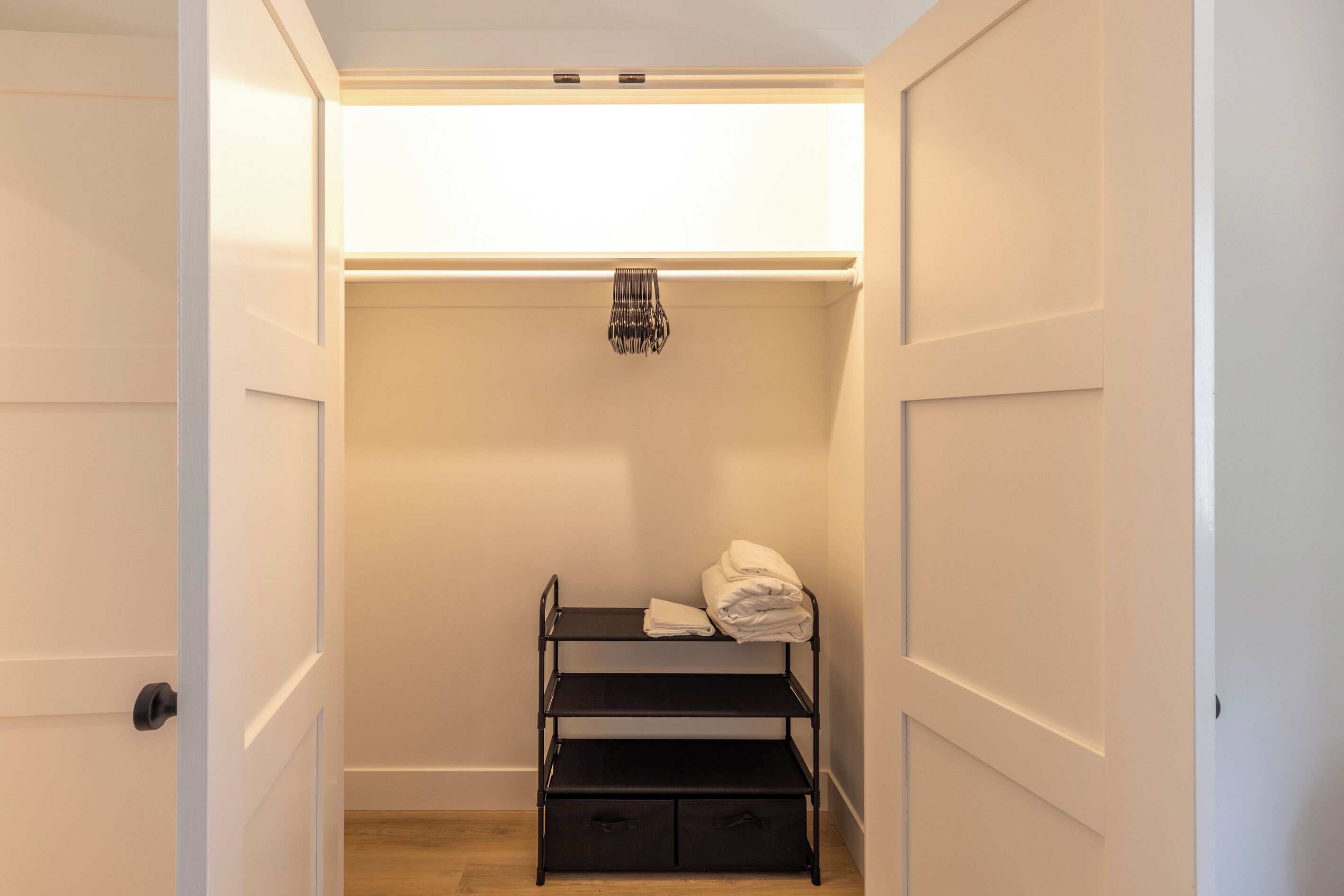 Un dressing avec une étagère en métal noir, une tringle à vêtements et une boîte de rangement.