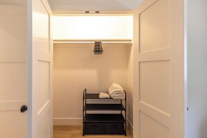 A walk-in closet with a black metal shelf unit, a hanging rack, and a storage box.