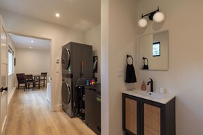 A modern kitchen with a built-in fridge, a dining area with a table and chairs, and a bathroom with a sink and towel rack. - Pond-View Guest House | River Access, 2 Kings (Durango)