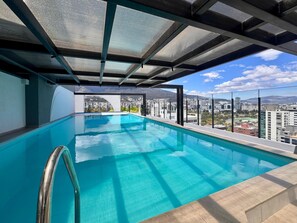 A rooftop infinity pool with a clear view of the cityscape and mountains in the background. - Vrbo Property (Quito)