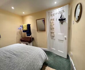 Una camera da letto con un letto, un armadio, uno specchio e una porta con porta asciugamani.
