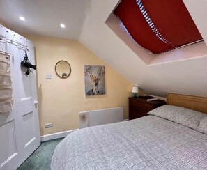 Una camera da letto con un letto, un comodino, una lampada, uno specchio a muro e un lampadario.